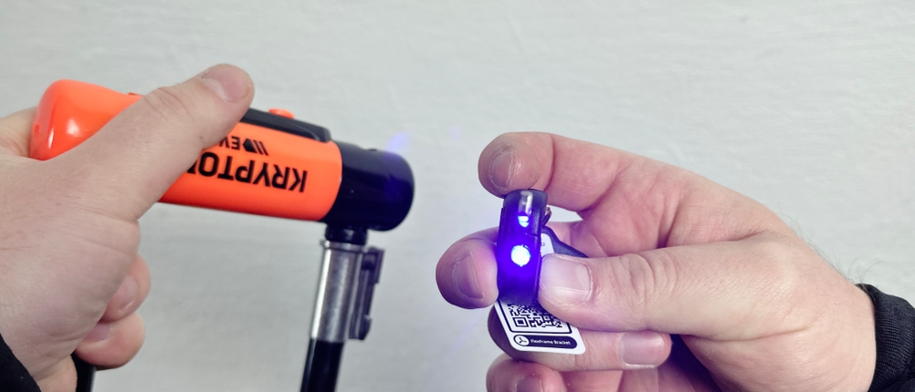 Eine Person hält einen Kryptonite-Schlüssel mit integrierter LED-Leuchte. Das Schloss befindet sich im Hintergrund.