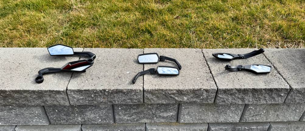 Drei Fahrradspiegelpaare liegen auf einer Steinmauer.