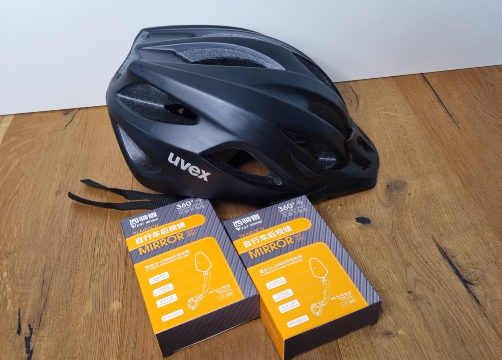 Chimona-Fahrrad-Spiegel auf einem Tisch neben einem Fahrradhelm. 