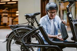 Fahrradversicherungen im Test: Ein älterer Herr bringt den Akku an seinem E-Bike an.