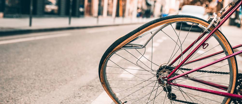 Fahrradversicherungen im Test: Der Reifen eines roten Fahrrads ist verbogen und demoliert.