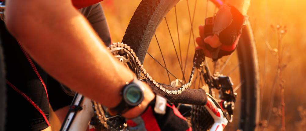 Eine Person mit Fahrradhandschuhen repariert die Kette eines Fahrrads.