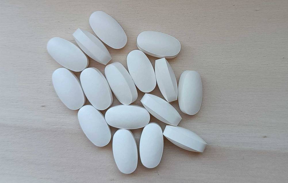 Im Test: Mehrere Tabletten Bromelain auf einer Holzfläche.