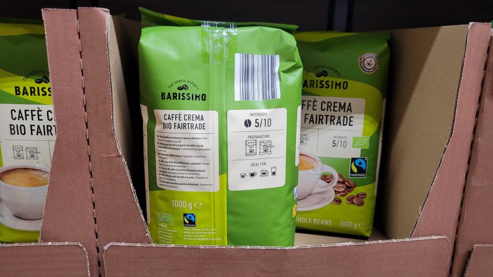 Mehrere Packungen der getesteten Fairtrade-Kaffeebohnen in einem Verkaufsregal, eine Packung steht mit der Rückseite nach vorne.