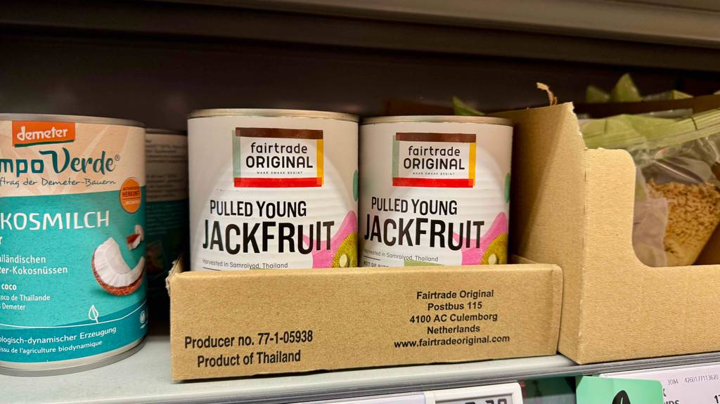 Jackfruit im Test: Mehrere Dosen stehen zwischen anderen Produkten in einem Regal.