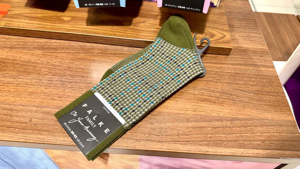 Ein Paar grün-gemusterte Falke-Socken liegt getestet auf einer Holzfläche.