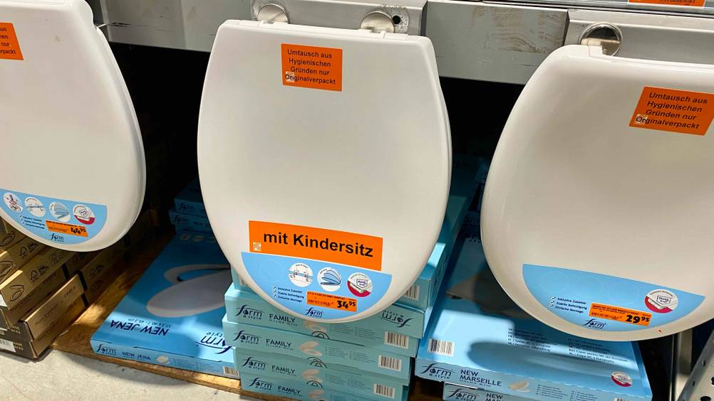 Familien-WC-Sitz im Test: Ein Sitz hängt neben anderen an einem Regal in einem Baumarkt.