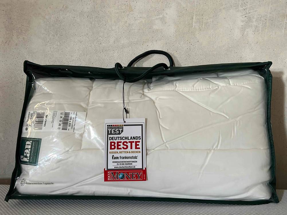 Bettdecke in 155x220 cm-Test: Das Produkt in seiner Originalverpackung vor einer Betonwand.