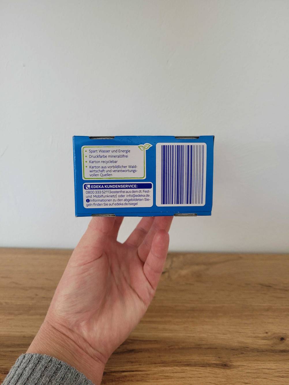 Seitenansicht einer Packung der getesteten Farbfangtücher von einer Hand nach oben gehalten.