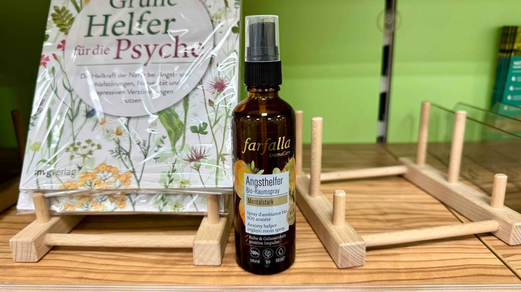 Eine Flasche Raumspray steht zum testen neben einem psychologischen Buch.