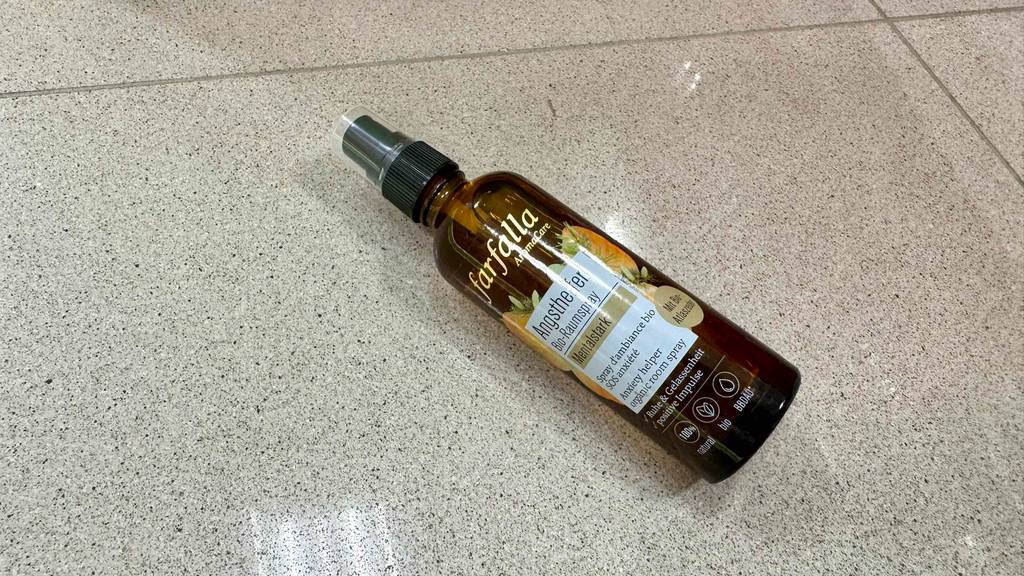 Eine Flasche getestetes Raumspray liegt quer auf Fliesen.