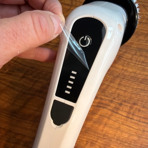 Eine Hand zieht eine Folie von der elektrischen Fari-Reinigungsbürste ‎ANS-8050
