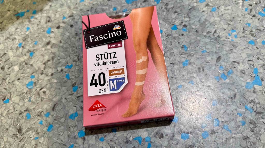 Die Verpackung einer getesteten Stützstrumpfhose liegt auf einem gesprenkelten Boden.
