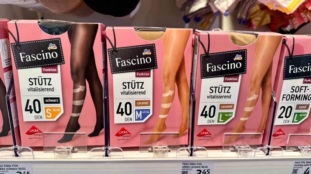 Stützstrumpfhose im Test: Mehrere Packungen unterschiedlicher Größen und Farben stehen neben- und hintereinander in einem Regal.