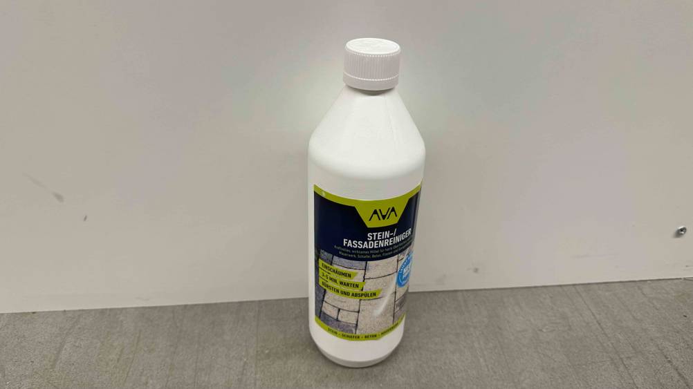Eine Flasche des getesteten Fassadenreinigers vor einer hellen Wand mit Fokus auf den Verschluss.