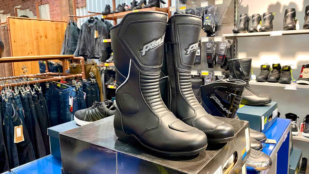Motorradstiefel getestet: Zwei Stiefel von der Seite auf einem Karton im Hintergrund viele andere Schuhe.