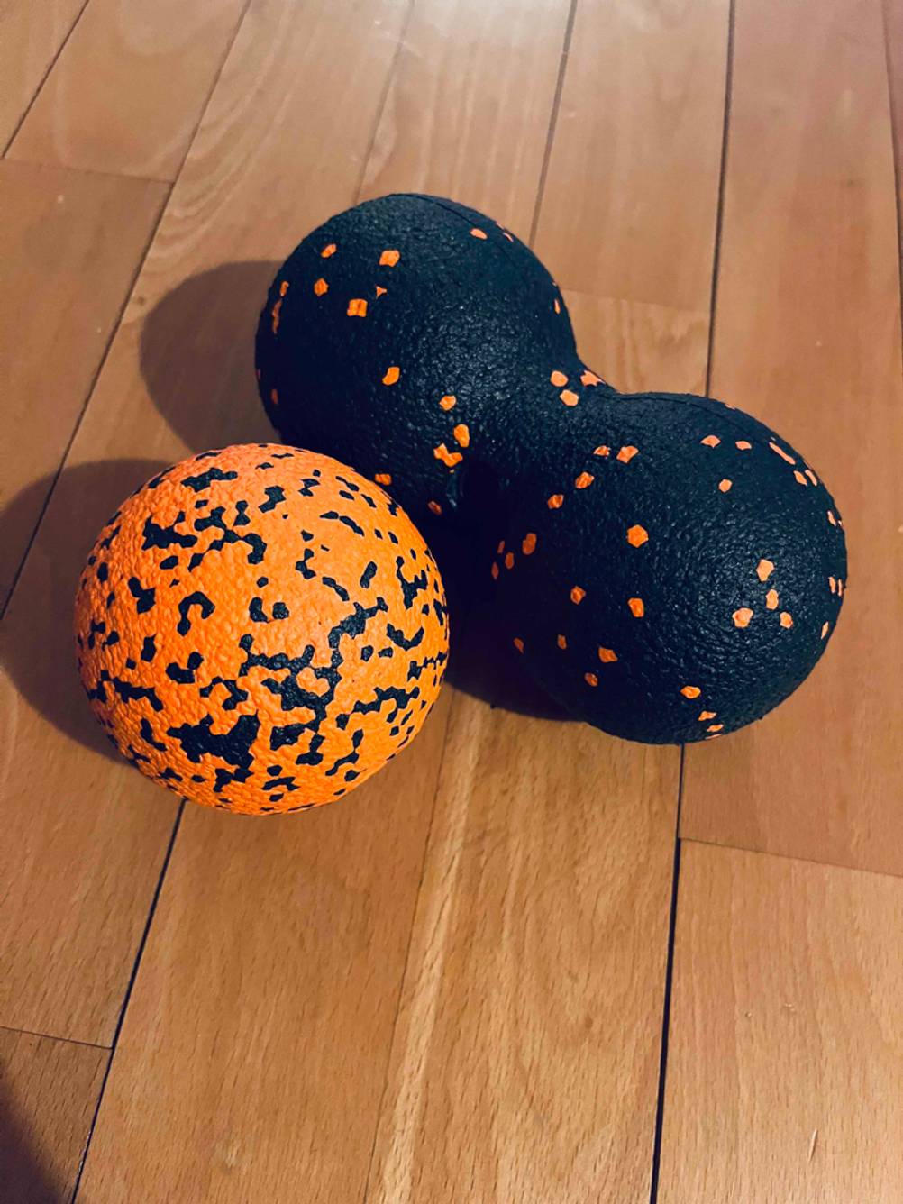 Faszienball-Test: Im Test: Zwei unterschiedliche Faszienbälle nebeneinander auf einem Holzboden.