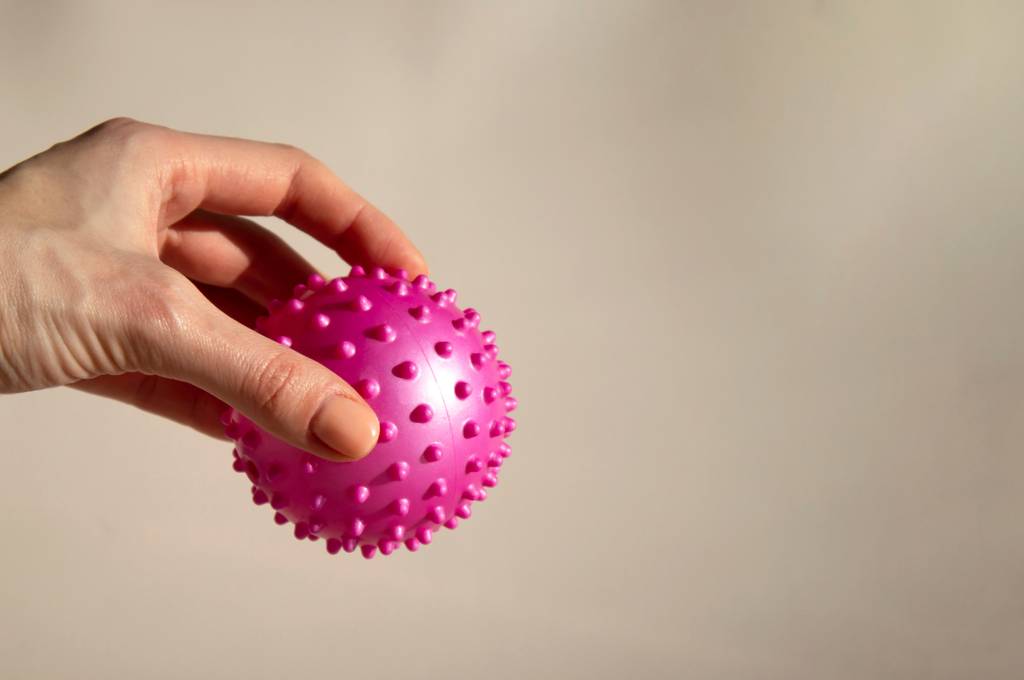 Faszienrollen-Set-Test: Eine Frau hält einen pinken Lacrosseball in der Hand.