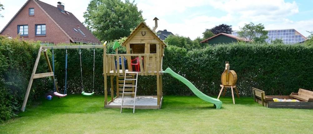 Fatmoose-Spielturm-Test: Ein Spielturm mit einer grünen Rutsche in einem Garten.