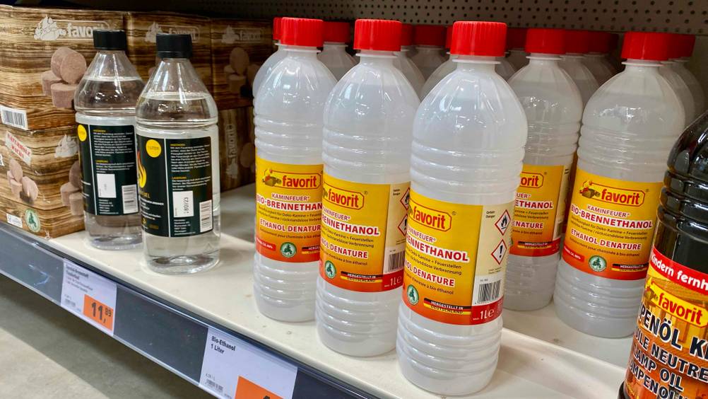 Getestet: Mehrere Flaschen Bioethanol stehen in einem Verkaufsregal zwischen anderen Produkten.