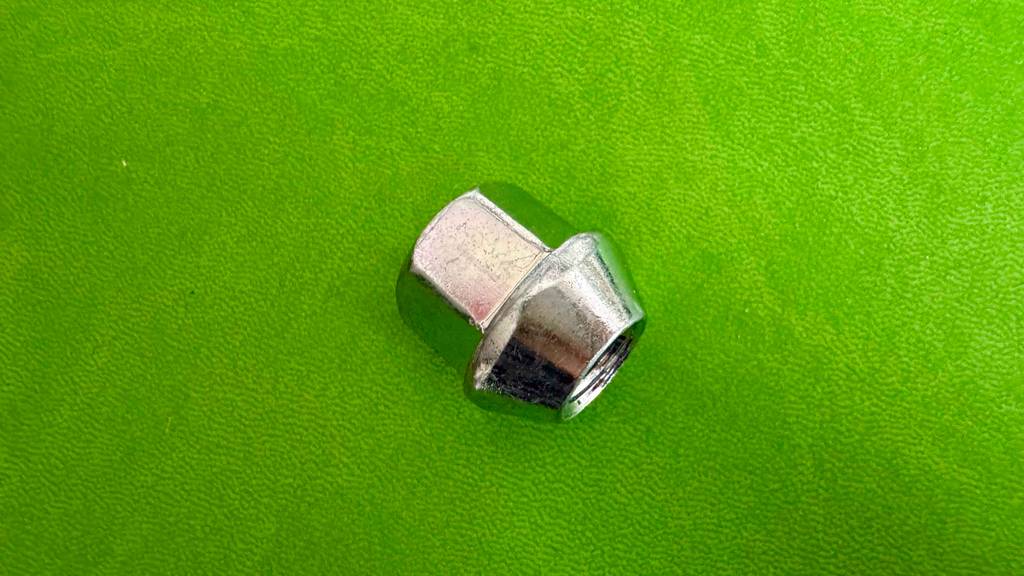 Detailansicht einer getesteten Radmutter, die auf einer grünen Fläche liegt.