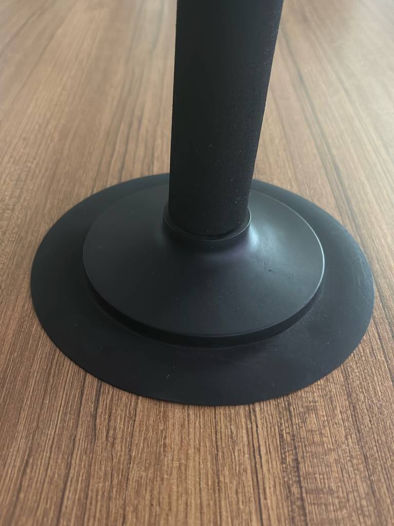 Nahaufnahme der schwarzen, runden Standfläche inklusive Ständer eines getesteten Punchingballs, auf einer Holzoberfläche stehend.