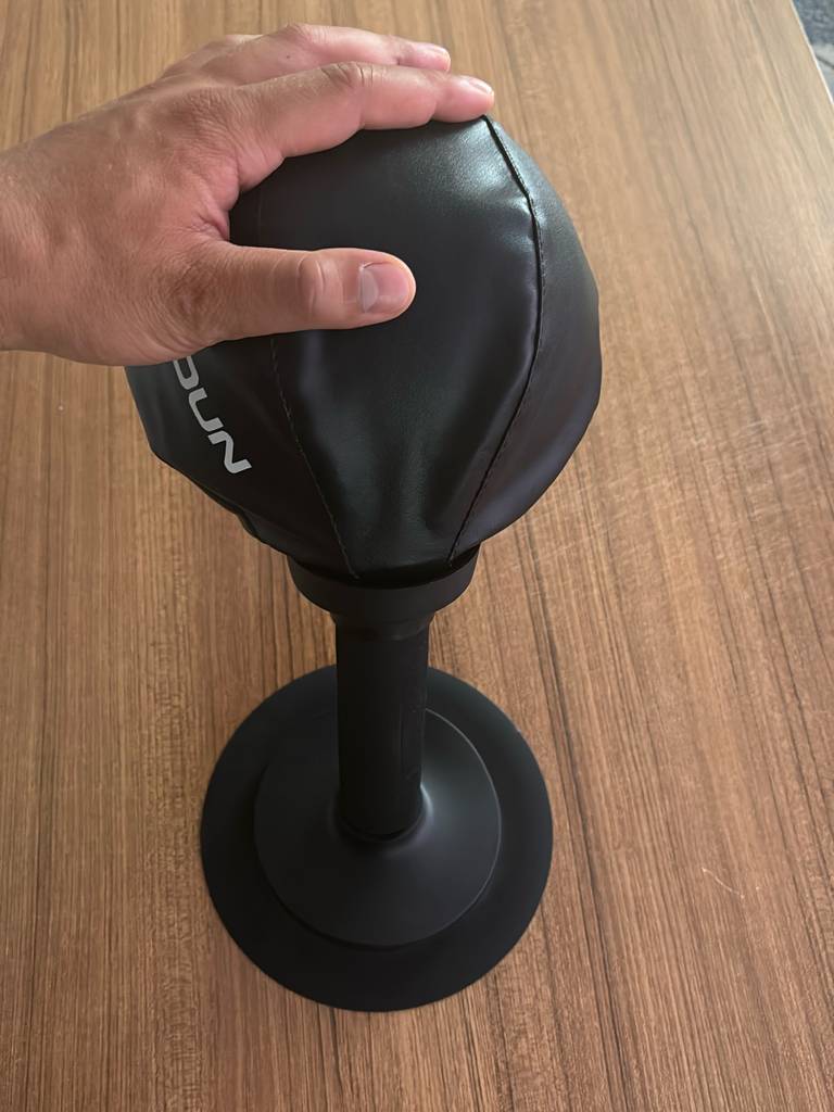 Eine Hand drückt einen getesteten Punchingball zur Seite, der auf einer Holzoberfläche steht.