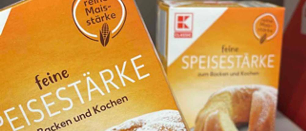 Im Test: Eine Hand hält eine Packung Speisestärke vor einem Regal mit weiteren Packungen.