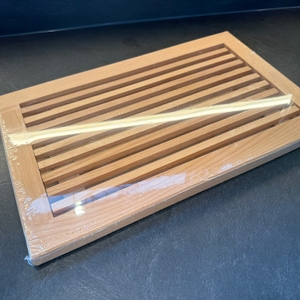 Das Feinholz-Brotschneidebrett liegt in seiner Verpackung auf einer Arbeitsplatte