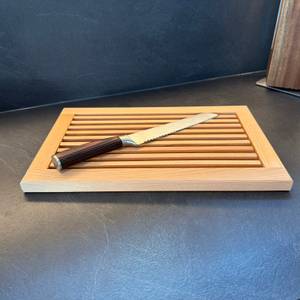 Ein Brotmesser liegt auf dem Feinholz-Brotschneidebrett