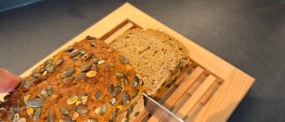 Brot wird auf dem Feinholz-Brotschneidebrett geschnitten