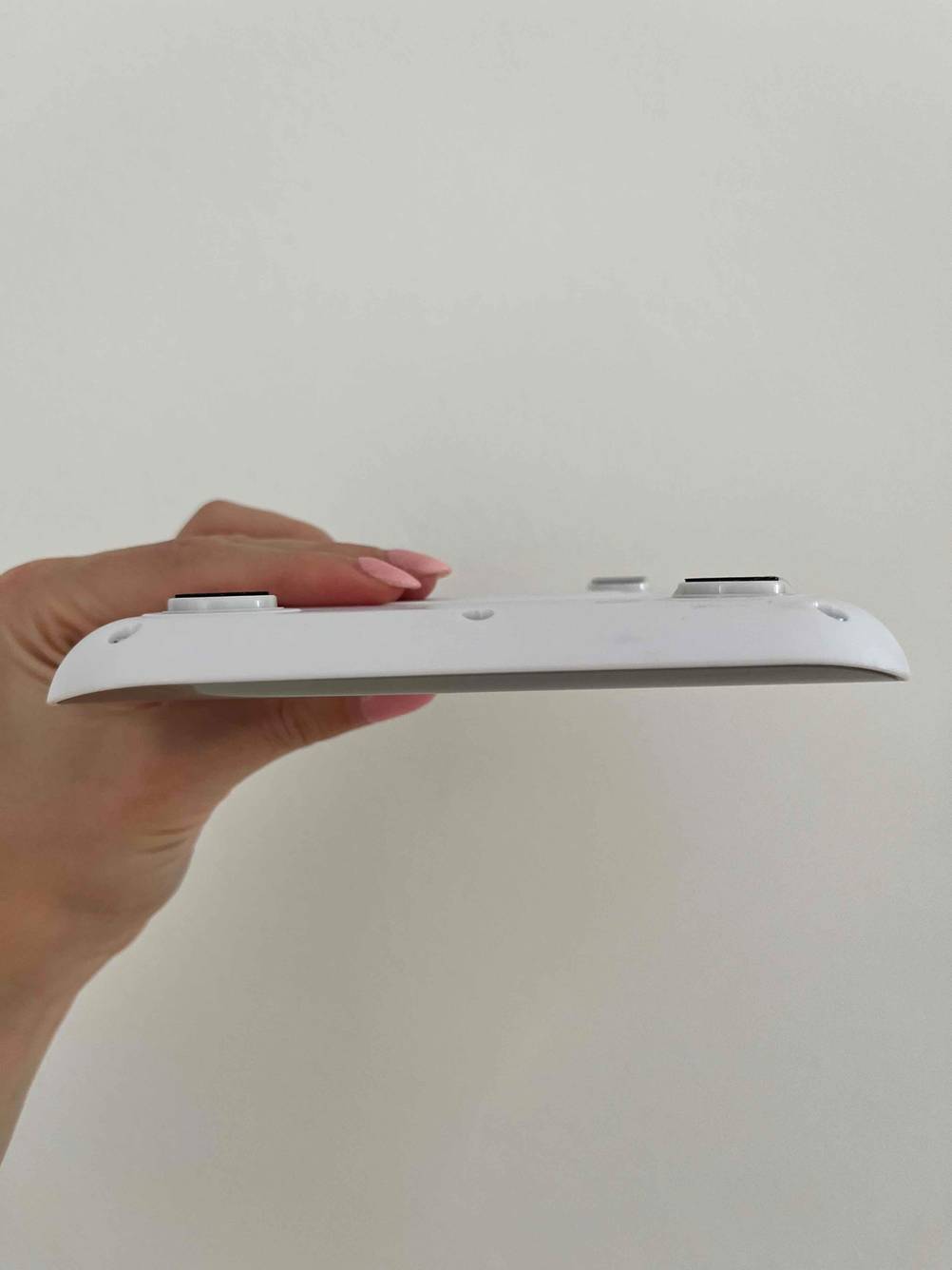 Im Test: Eine Hand hält eine Feinwaage mit der Unterseite nach oben zwischen den Fingern.