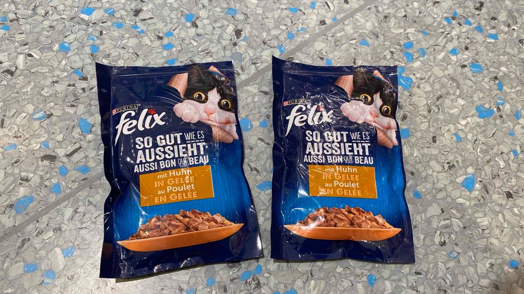Getestet: zwei Einzelbeutel Felix Sensations Katzenfutter mit Geschmacksrichtung Huhn liegen auf einem gesprenkelten, hellen Untergrund.