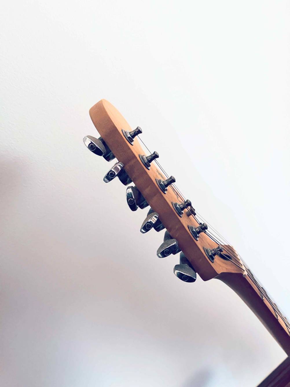 Seitenansicht der Kopfes einer getesteten E-Gitarre vor einer weißen Wand.