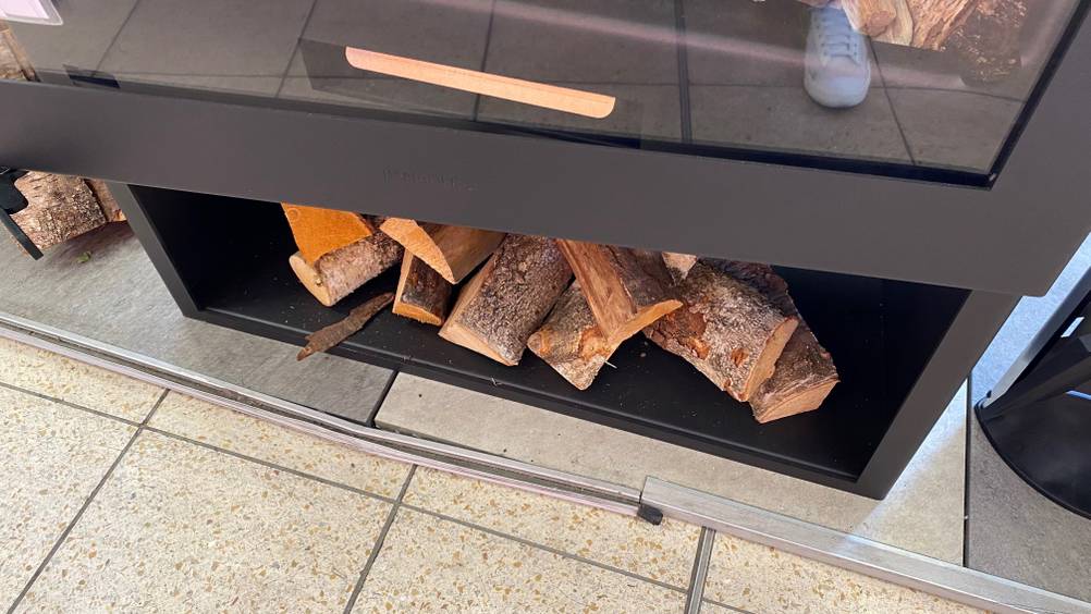 Kaminofen Fenix getestet: Im Regalfach liegt Holz.