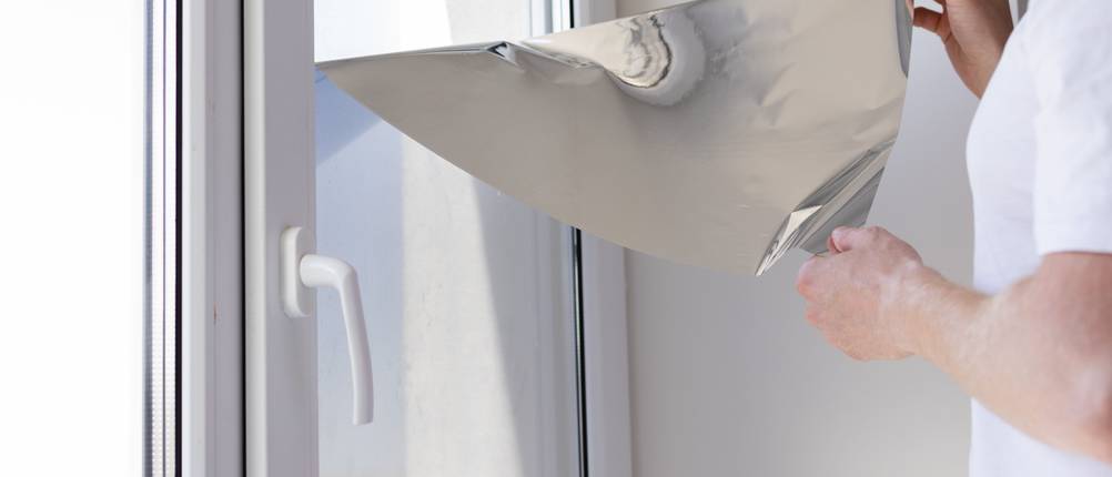 Fensterfolie-Test: Mann löst Sonnenschutz-Fensterfolie vom Fenster