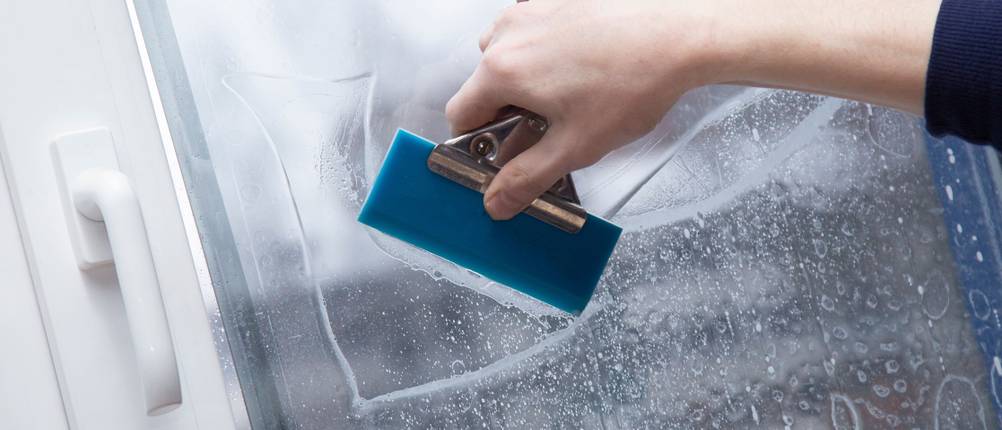 Fensterfolie-Test: Fensterfolie wird mit Schaber auf feuchte Scheibe aufgetragen.