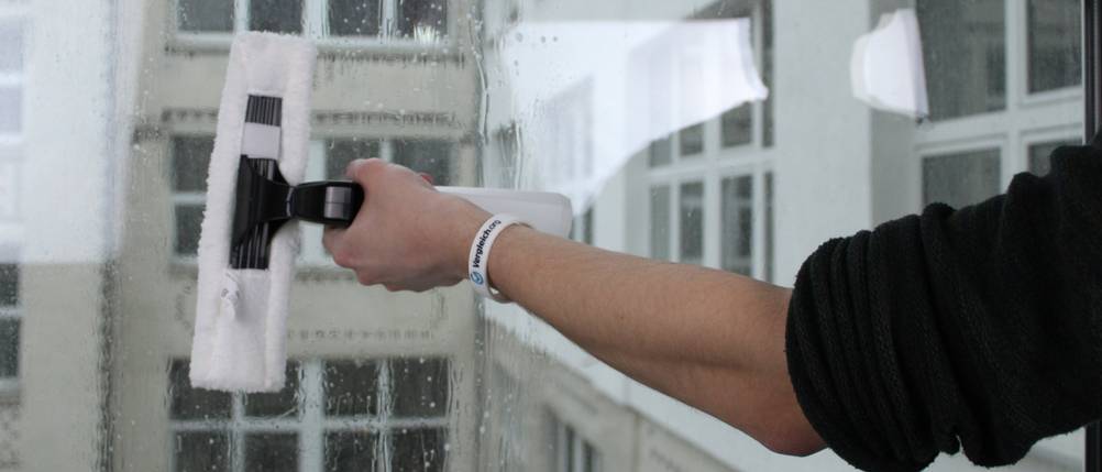Ein weißer Fenstersauger reinigt quer ein Fenster.