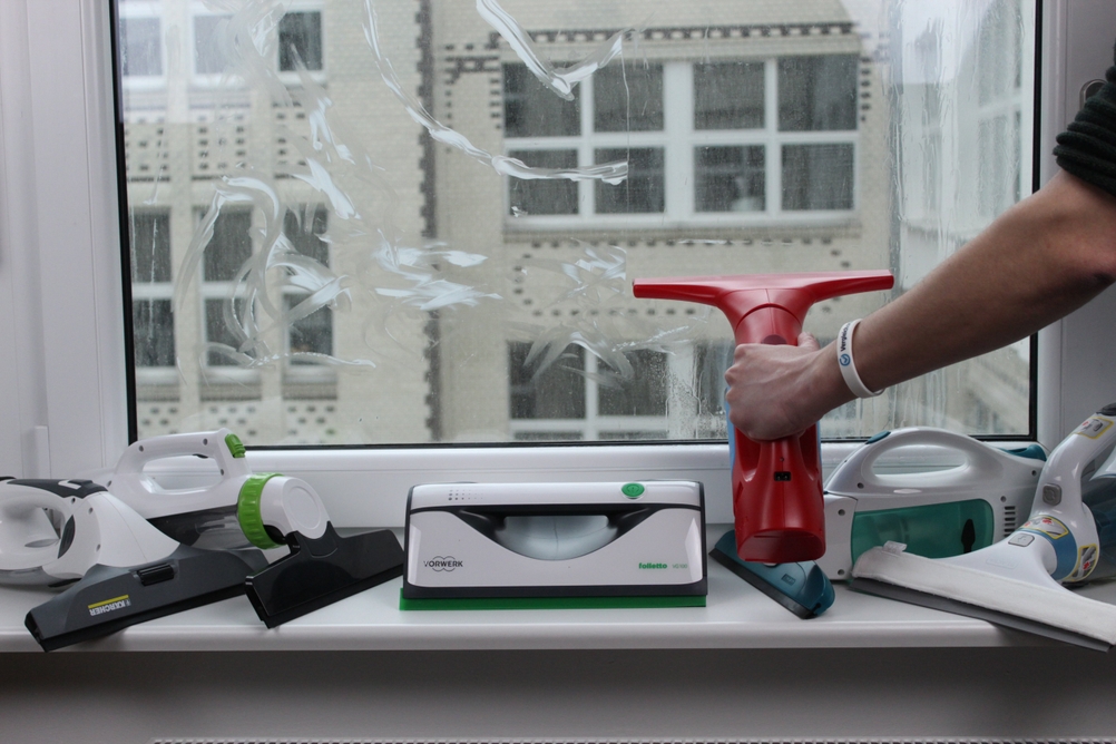 Ein roter Fenstersauger wird an einem Fenster verwendet.