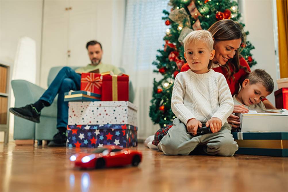 Ferngesteuerte Autos ab 3 Jahre im Test: Hier eine Familie an Weihnachten. Der Junge hat ein rotes ferngesteuertes Auto bekommen.