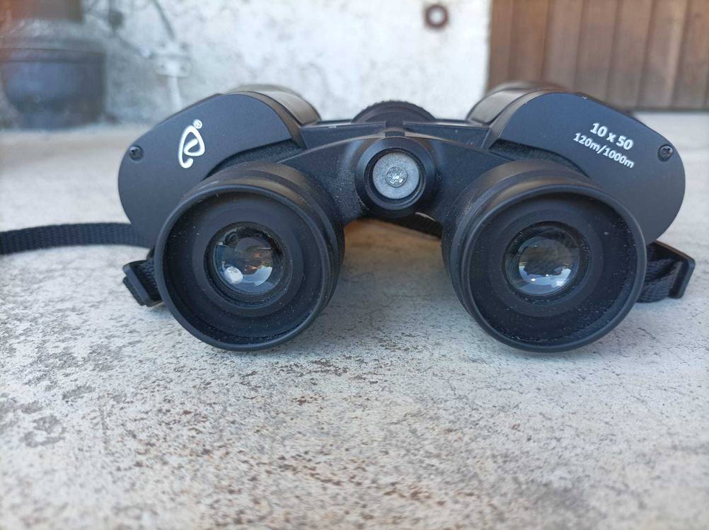 Das getestete Fernglas 10x50 von vorne auf einem Betonboden liegend.