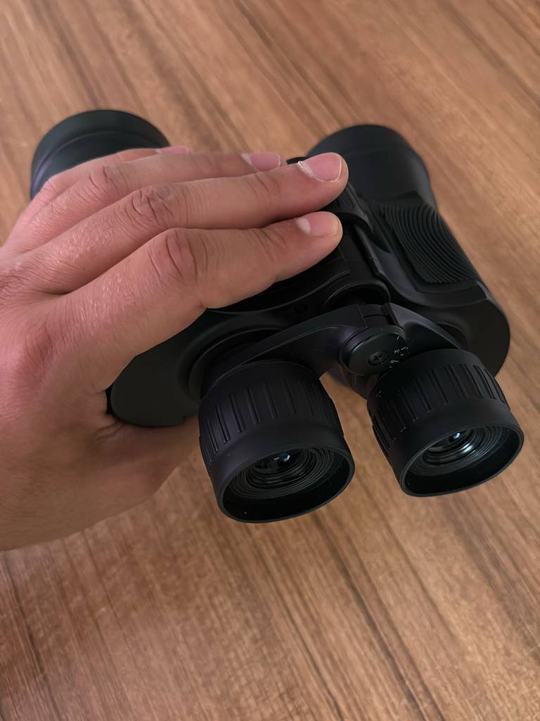Eine Hand hält ein Fernglas 16x32 zum testen.