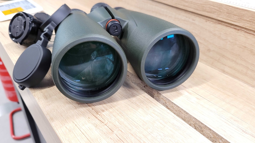 Ein getestetes Fernglas von vorne auf einem Holzregal liegend.