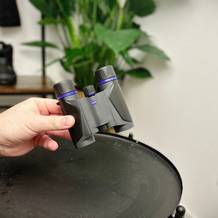 zeiss terra ed pocket Fernglas ohne Schutzhülle von einer Hand über einem schwarzen Tisch gehalten.