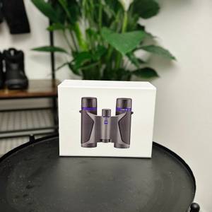 Die Originalverpackung des Zeiss-Terra-ED-Pocket-Fernglases steht auf einem Tisch. Die Verpackung zeigt ein Bild des Fernglases und hebt seine kompakte Bauweise hervor.