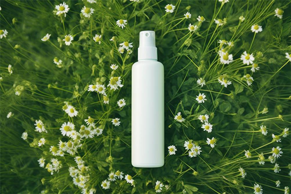 Fernhaltespray für Hunde im Test: Eine Sprühflasche, die auf einer blumigen Wiese liegt.