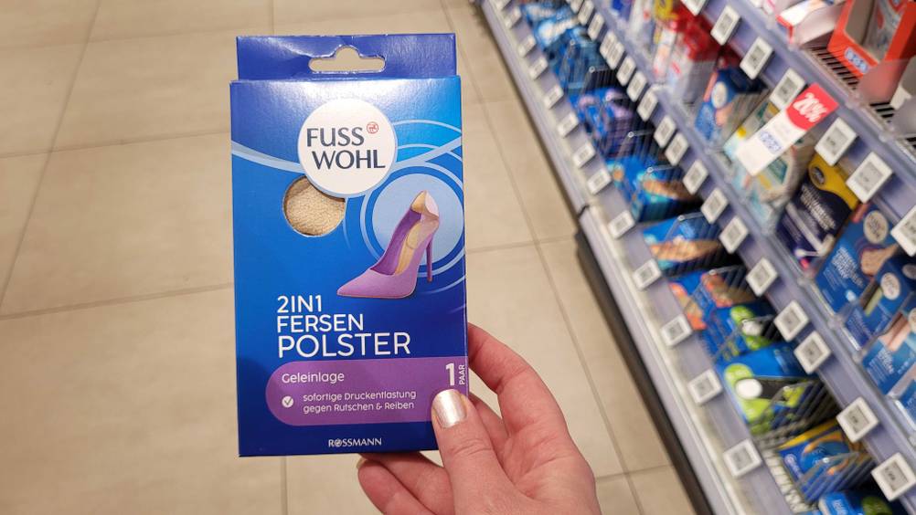 Eine Hand hält eine Packung der getesteten Fersenpolster vor ein Verkaufsregal.