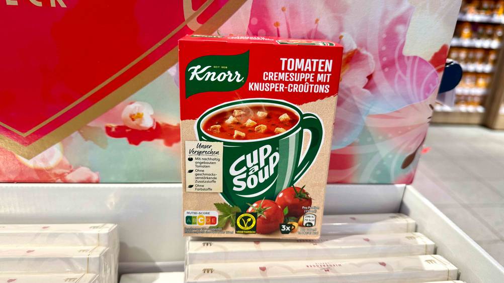 Vor einem Plakat auf einem Aufsteller steht eine Packung der getesteten Fertigsuppe.