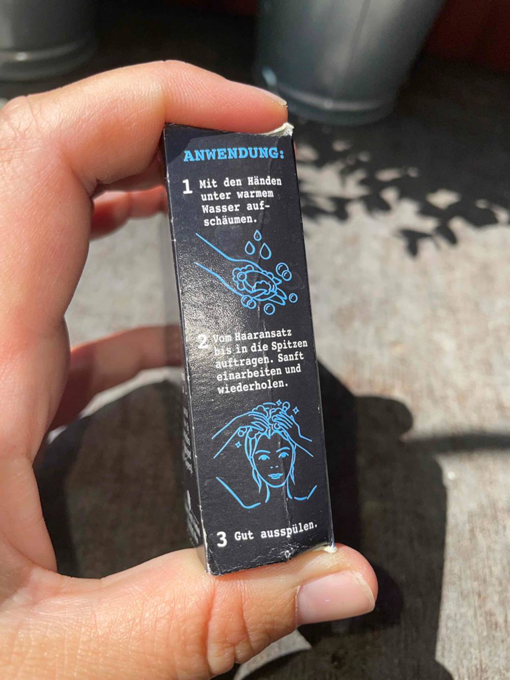 Seitenansicht einer Packung des getesteten festen Shampoos von einer Hand gehalten.