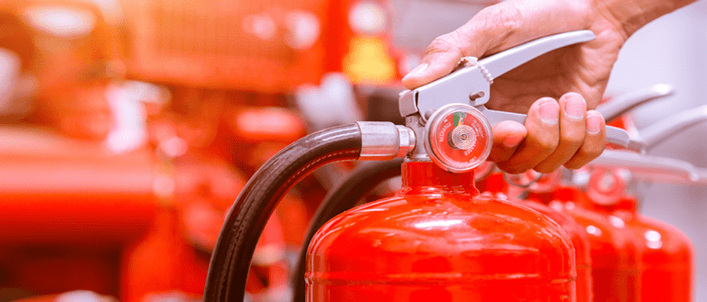Fettbrandlöscher getestet: Hand am Hebel eines Feuerlöschers.